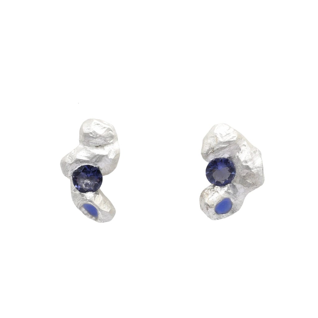 Kleine organisch geformte Ohrstecker aus Silber, blauem Iolith und einem Punkt aus blauem Lack.